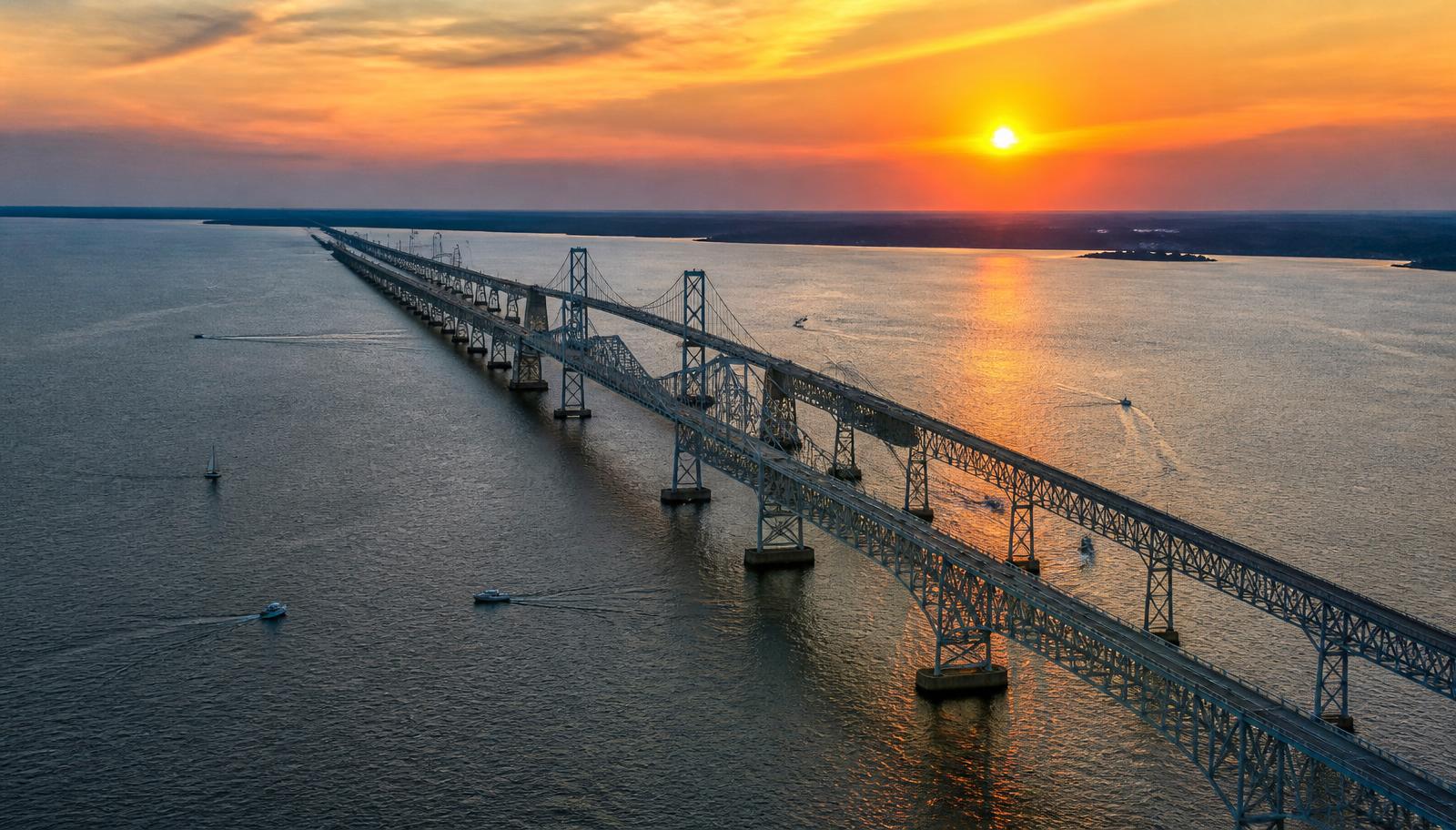 Aerial view of the twin-span Chesapeake Bay Bridge in Maryland at sunset with boats on the water