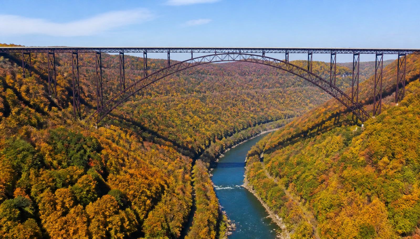 New River Gorge Bridge steel arch high above the tree-lined river gorge in autumn